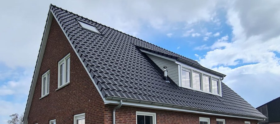 Nieuwbouwwoning met traditionele bakstenen gevel en witte kozijnen en zonnepanelen.