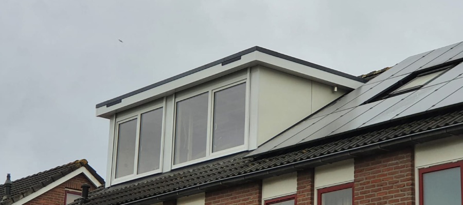 Een prefab dakkapel met twee ramen geïnstalleerd op een huis, gezien vanaf de buitenkant.