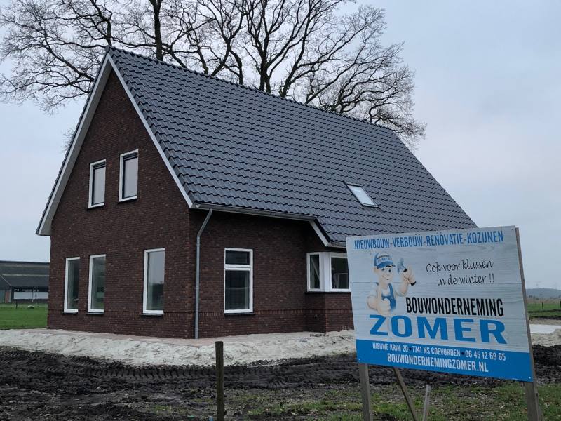 Nieuwbouwwoning met ernaast een reclamebord voor Bouwonderneming Zomer.