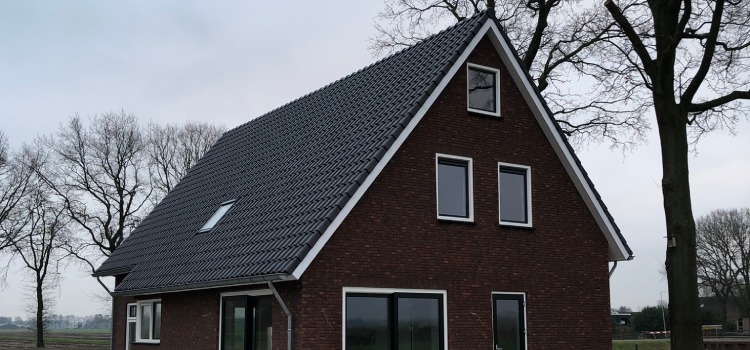 Prefab bouwen biedt vele voordelen Prefab huis in landelijke omgeving met donkere gevelstenen en wit kozijnwerk