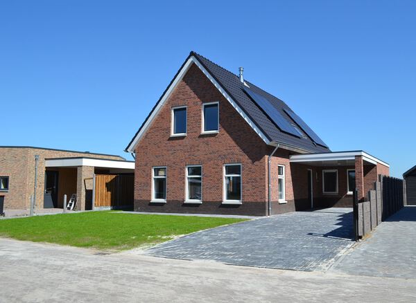 Vrijstaande woning met pannendak, zonnepanelen en carport bij bouwbedrijf in Gramsbergen.