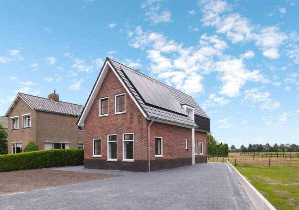 Bakstenen woning met dakkapel, zonnepanelen en oprit bij bouwbedrijf in Hardenberg.