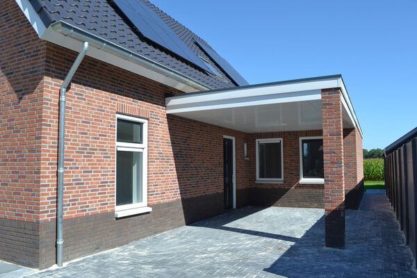 Bakstenen woning met aangebouwde carport en betegelde oprit bij bouwbedrijf in Ommen.